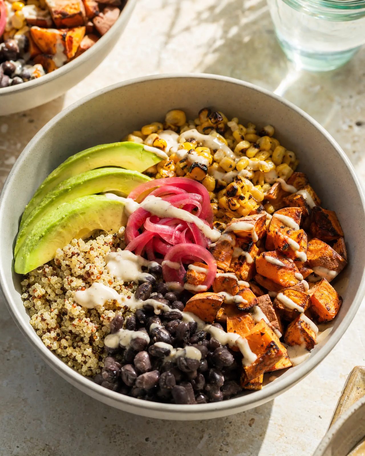 Bowl of quinoa, black beans, roasted sweet potato, corn, avocado and pickled red onion