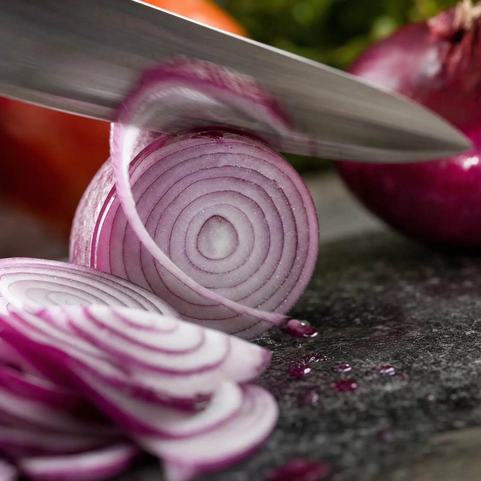 Knife slicing a red onion, macro